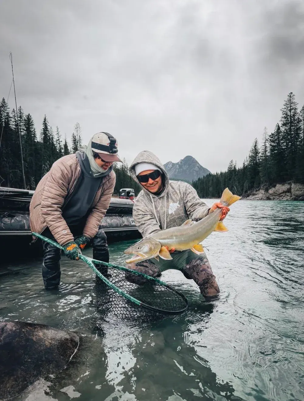 Angler in a Backcountry Skinz hoodie holding a fish